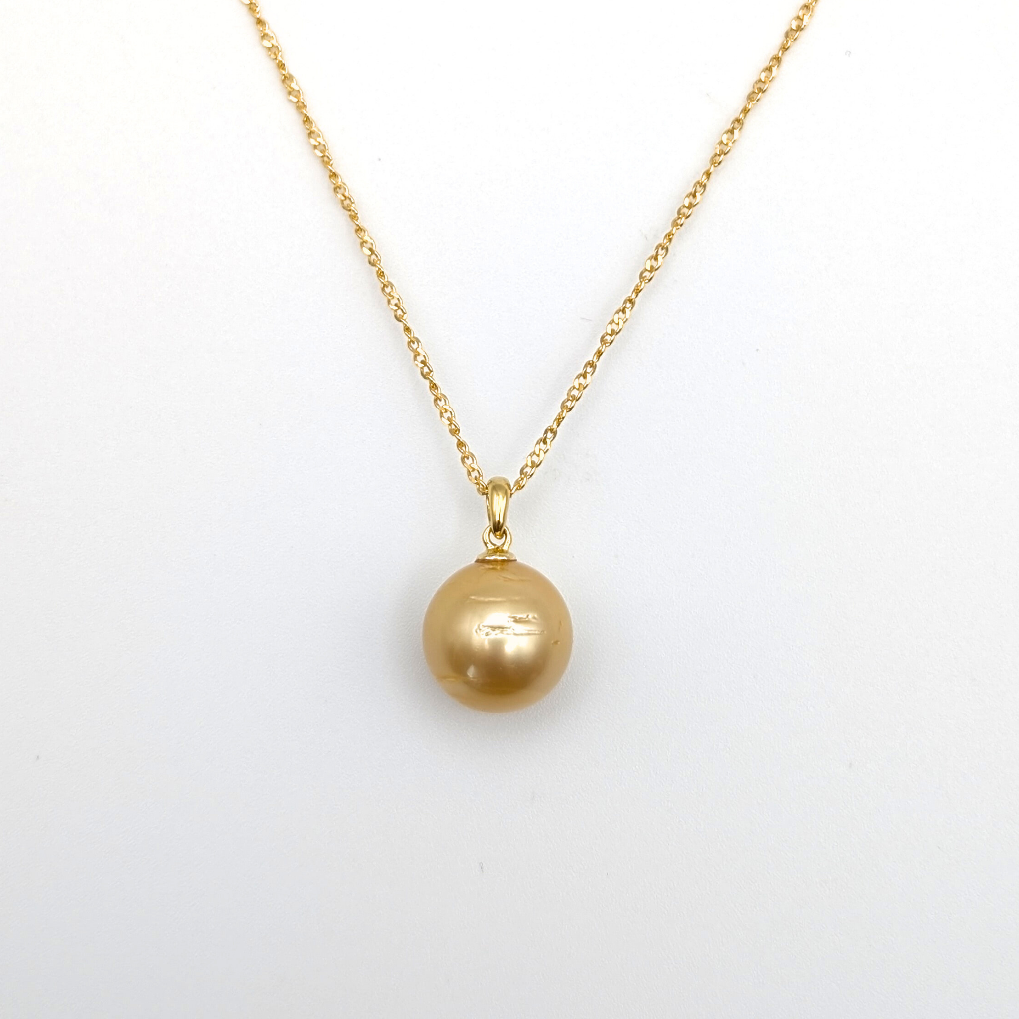 Gold necklace with a large gold south sea pearl pendant on a white background