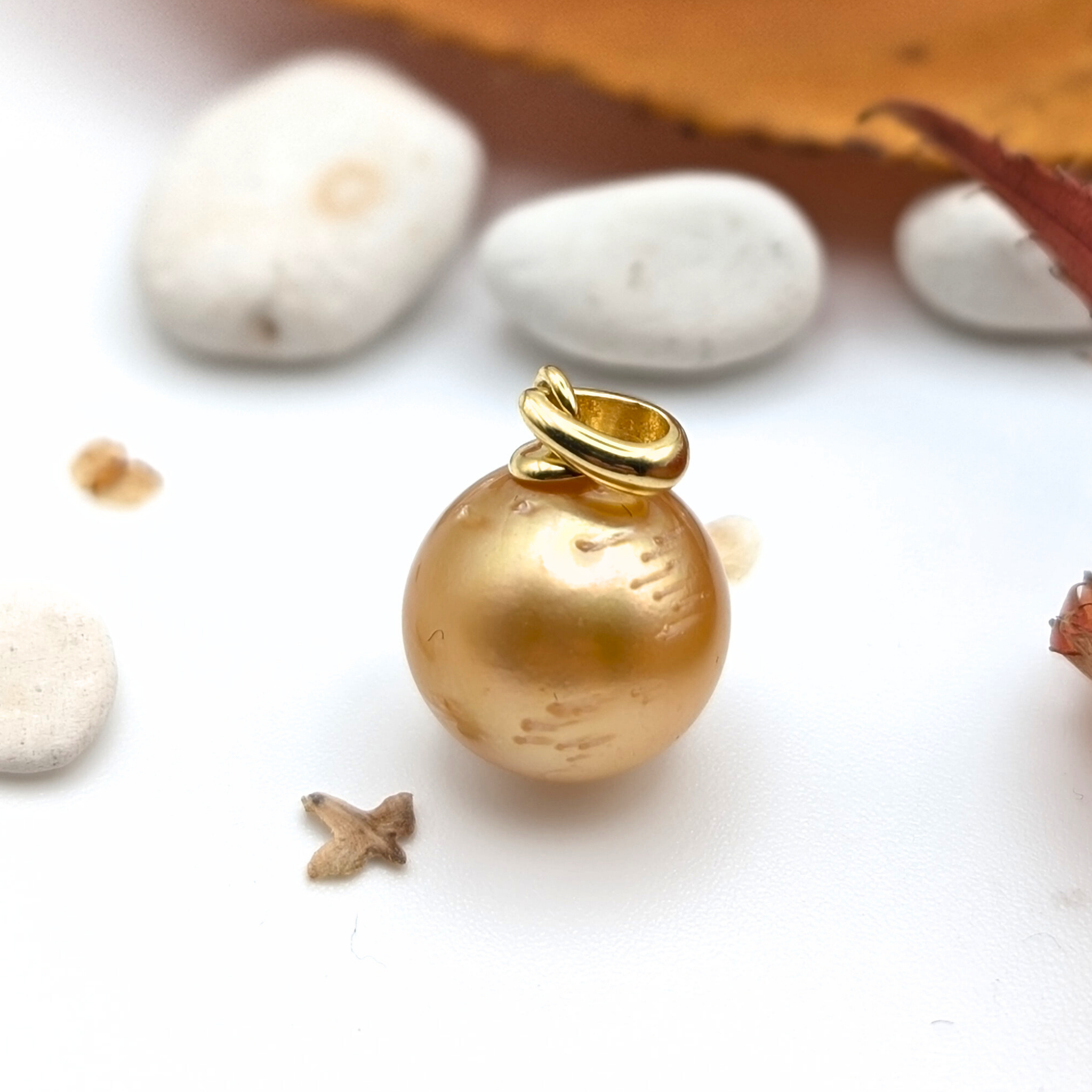 Gold south sea pearl pendant with pebble background 