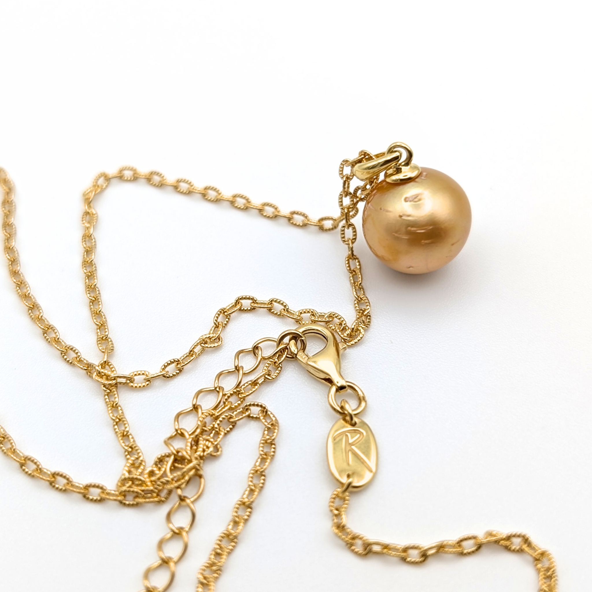 Gold necklace with a single golden south sea pearl pendant on a white background