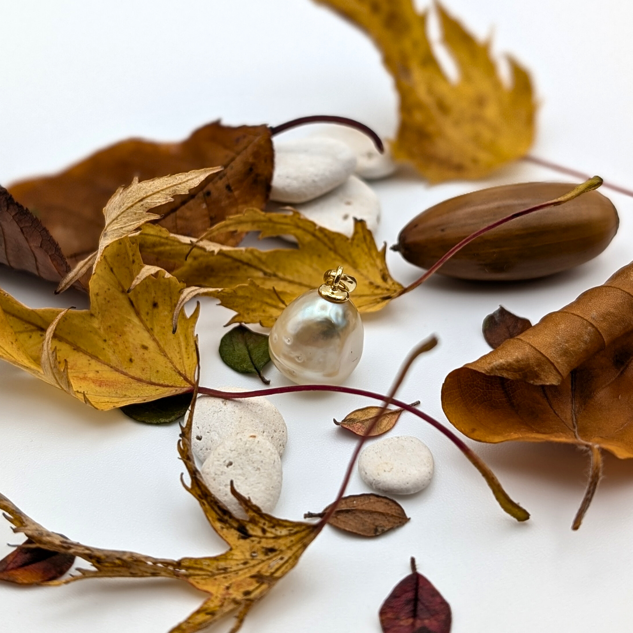 gold spotted south sea pearl pendant with gold vermeil bail and lifestyle background with stones and leaves