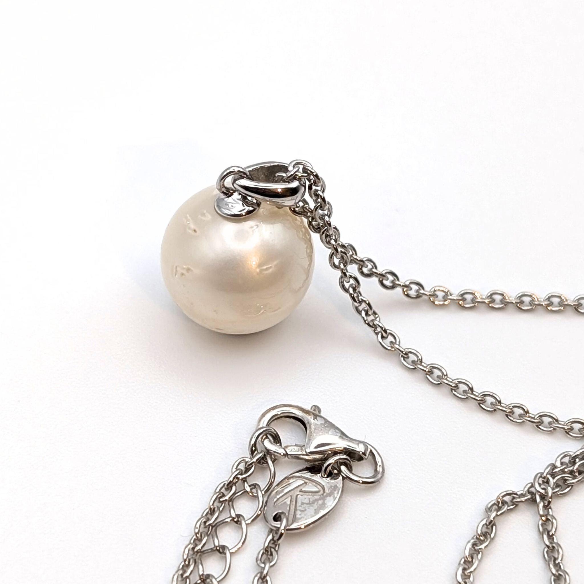 Rhodium plated sterling silver necklace with a large white spotted south sea pearl pendant on a white background