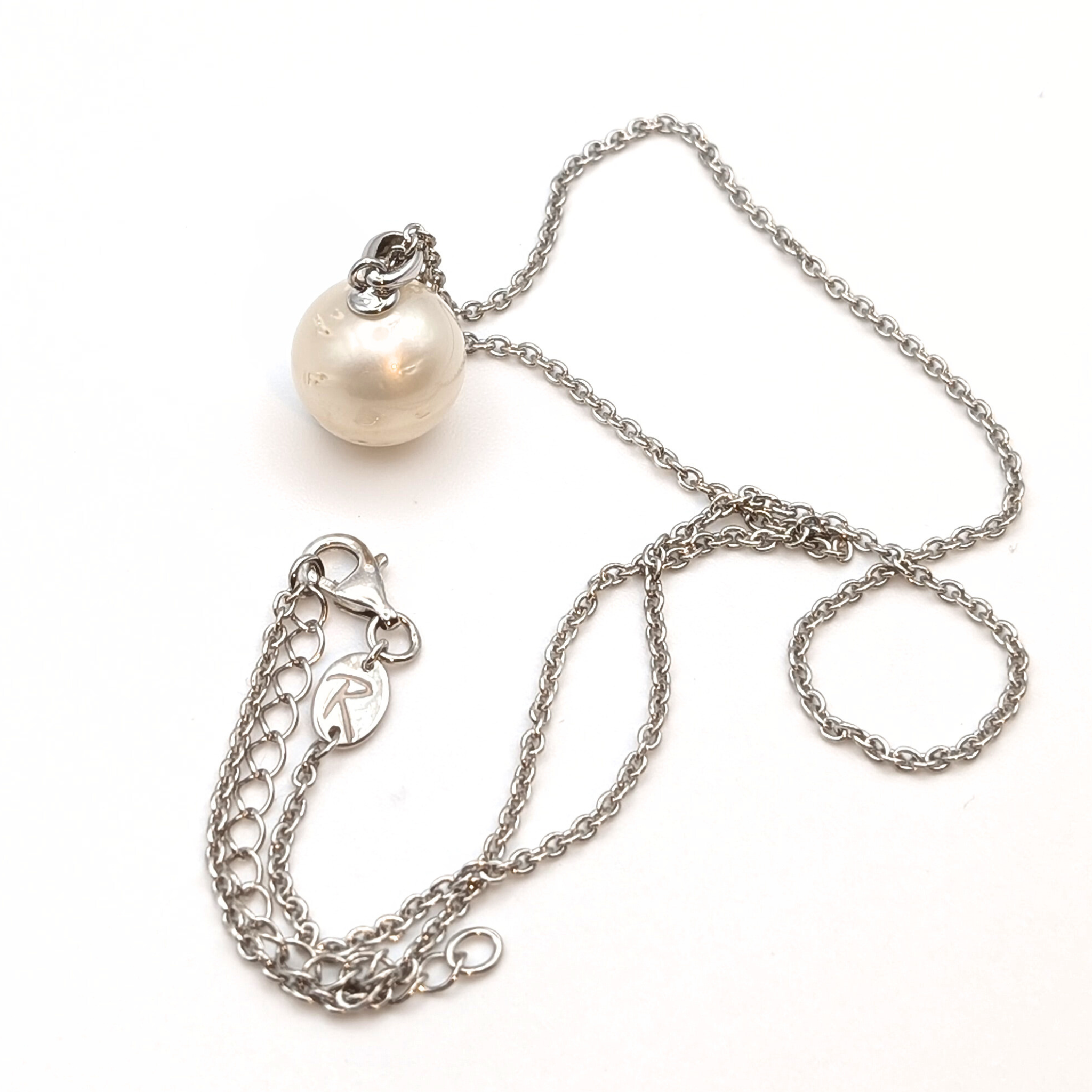 Rhodium plated sterling silver necklace with a large white spotted south sea pearl pendant on a white background