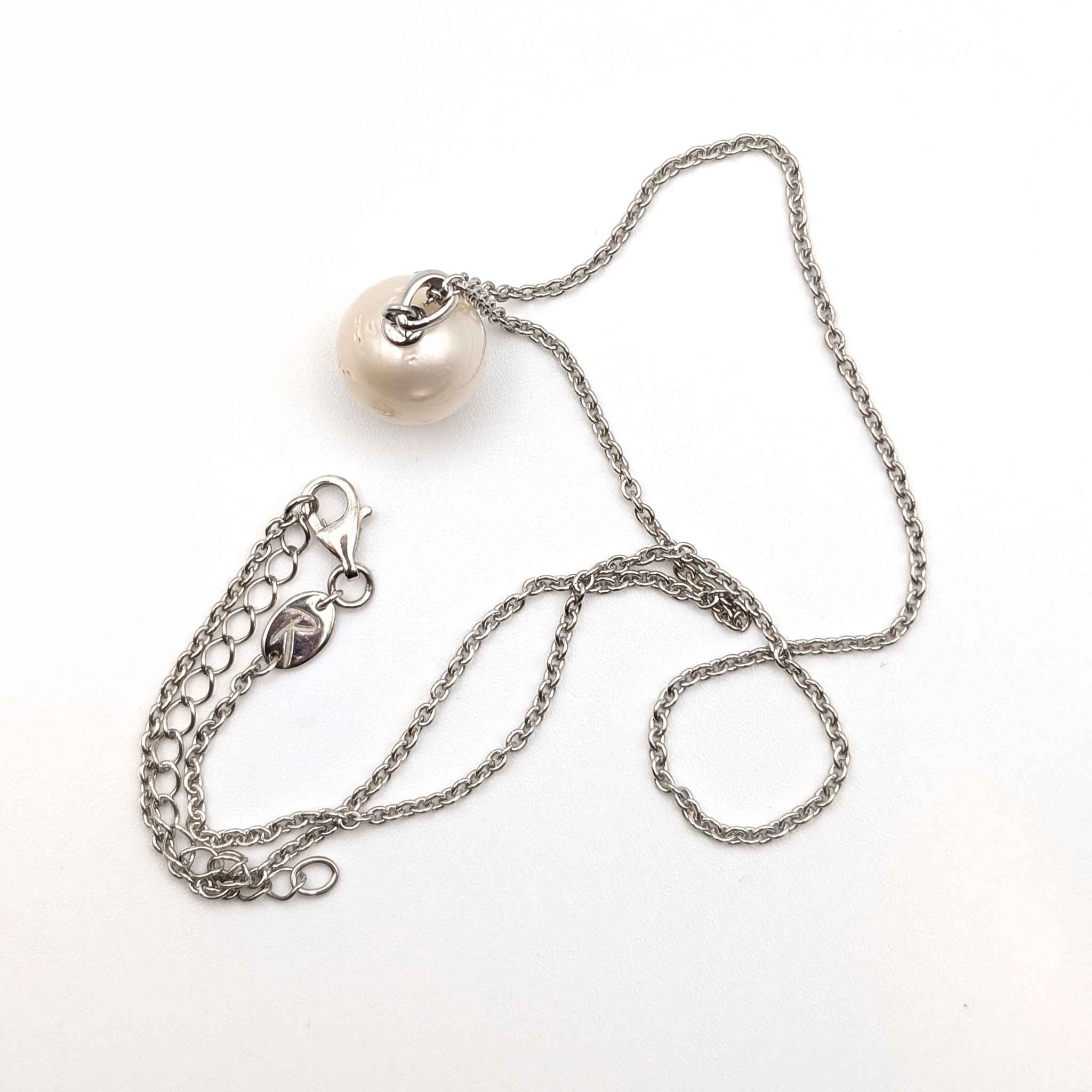 Rhodium plated sterling silver necklace with a large white spotted south sea pearl pendant on a white background