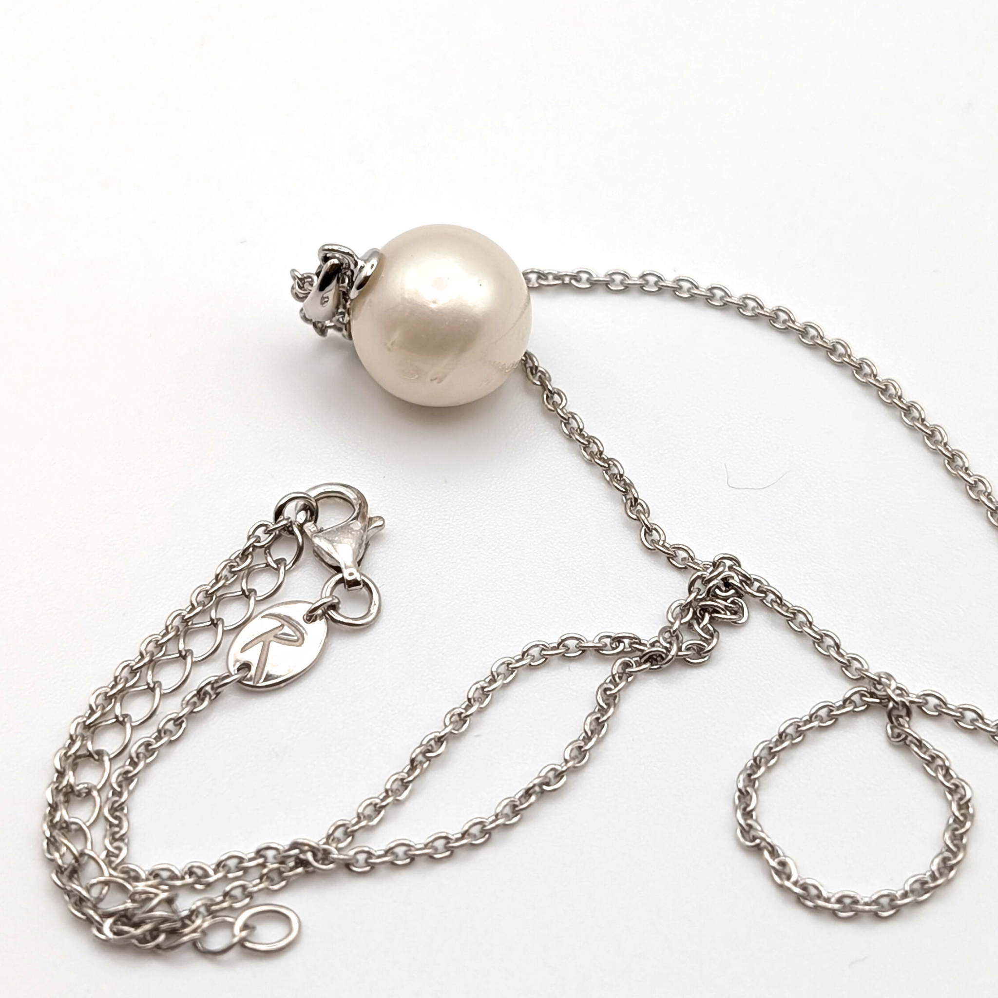 Rhodium plated sterling silver necklace with a large white spotted south sea pearl pendant on a white background